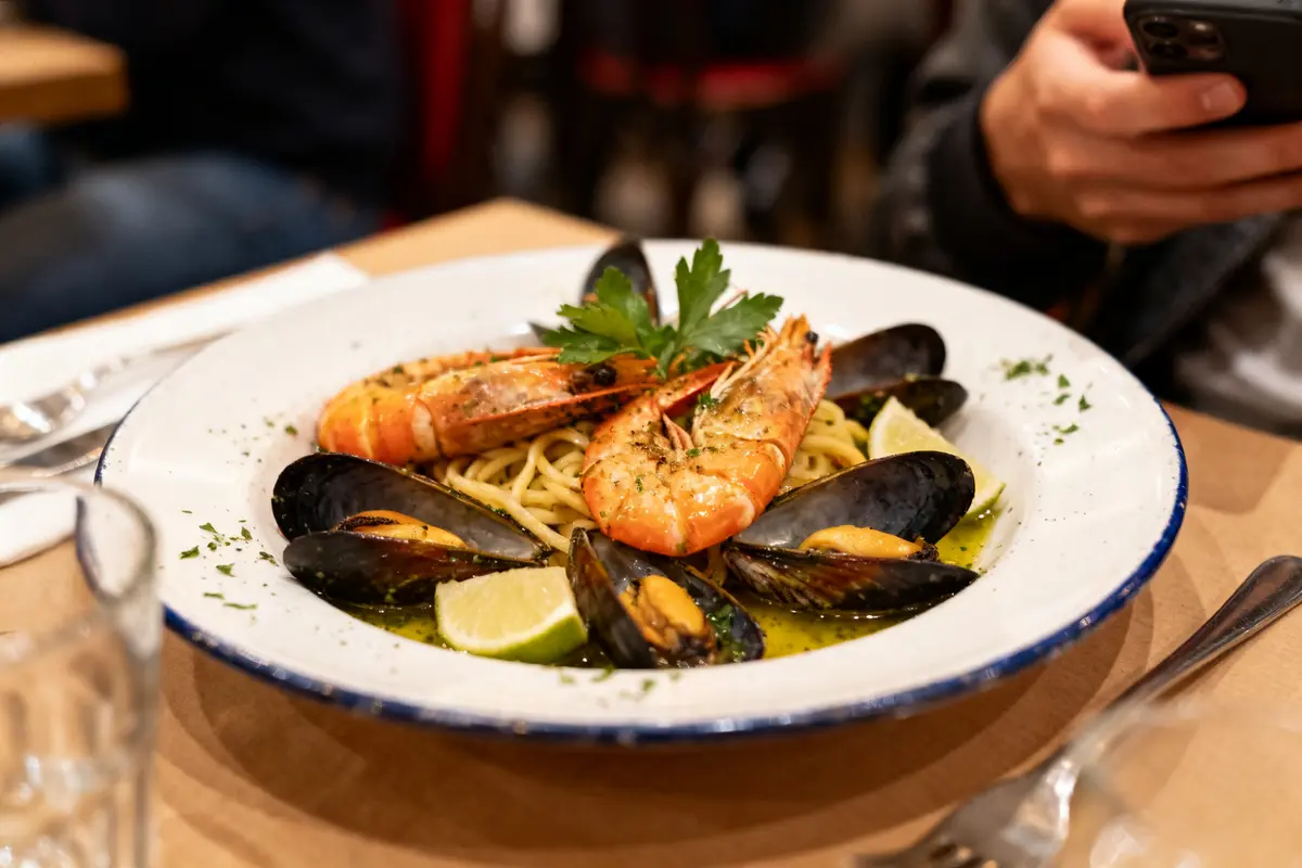 Assiette de fruits de mer avec pâtes et crevettes chez Monna sur une table